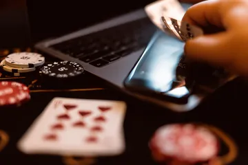 A woman smiling by bright slot machines showing lucky symbols, showcasing the exciting slot offerings at BB444.